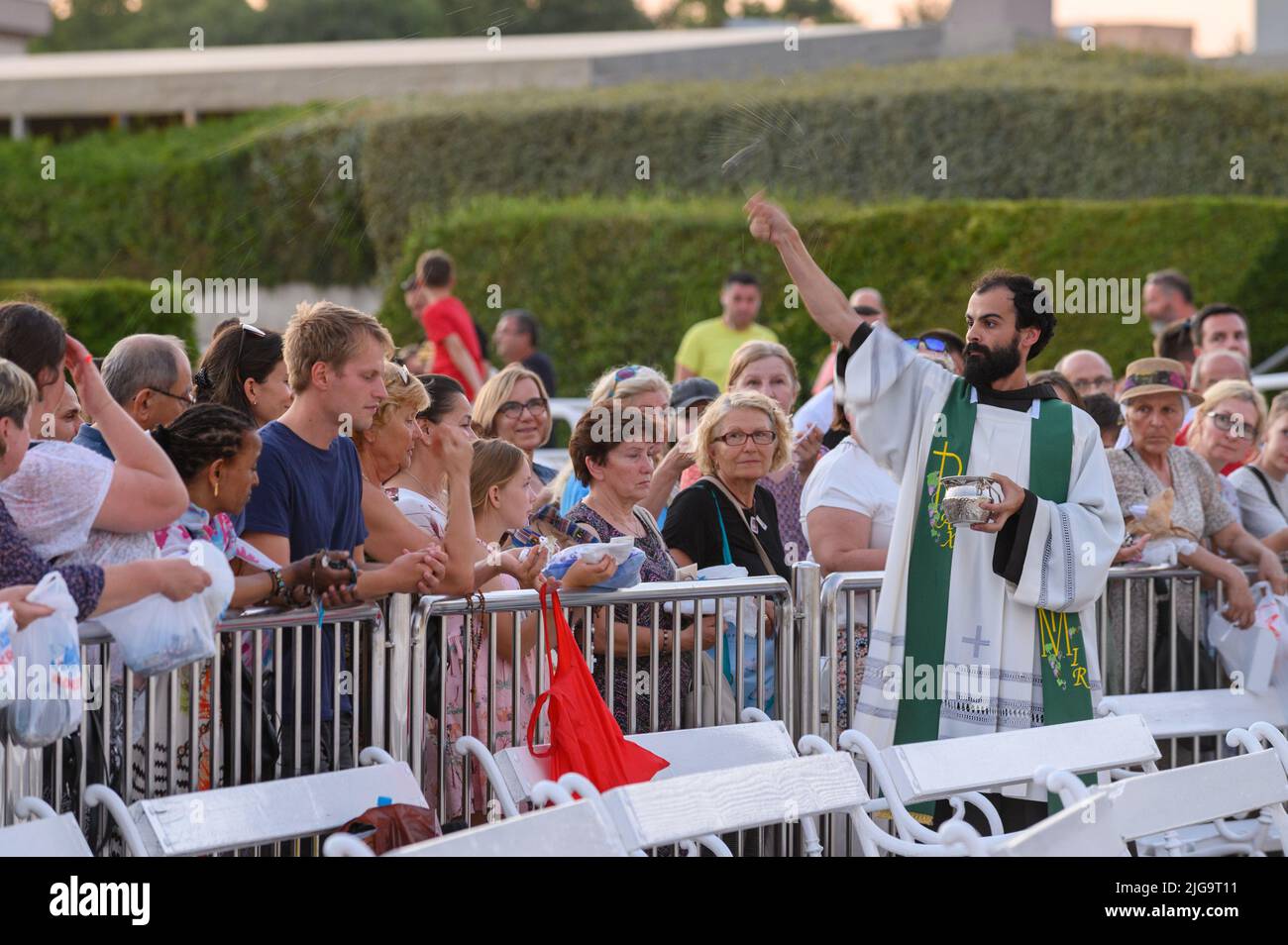 Un sacerdote che benedice gli articoli religiosi dei fedeli dopo la Santa Messa di sera a Medjugorje. Foto Stock