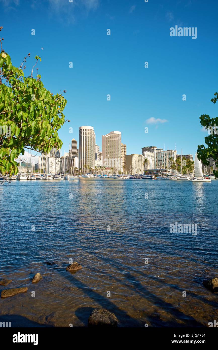 Appartamenti o quartiere degli affari accanto ad una spiaggia laguna in una giornata di sole con un cielo blu nuvoloso in Waikiki. Una popolare località turistica estiva in Foto Stock