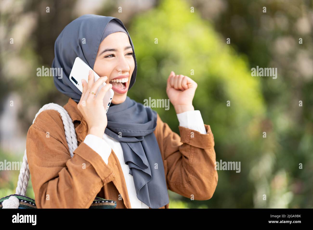 La donna musulmana alza il pugno per festeggiare con la mobilità Foto Stock