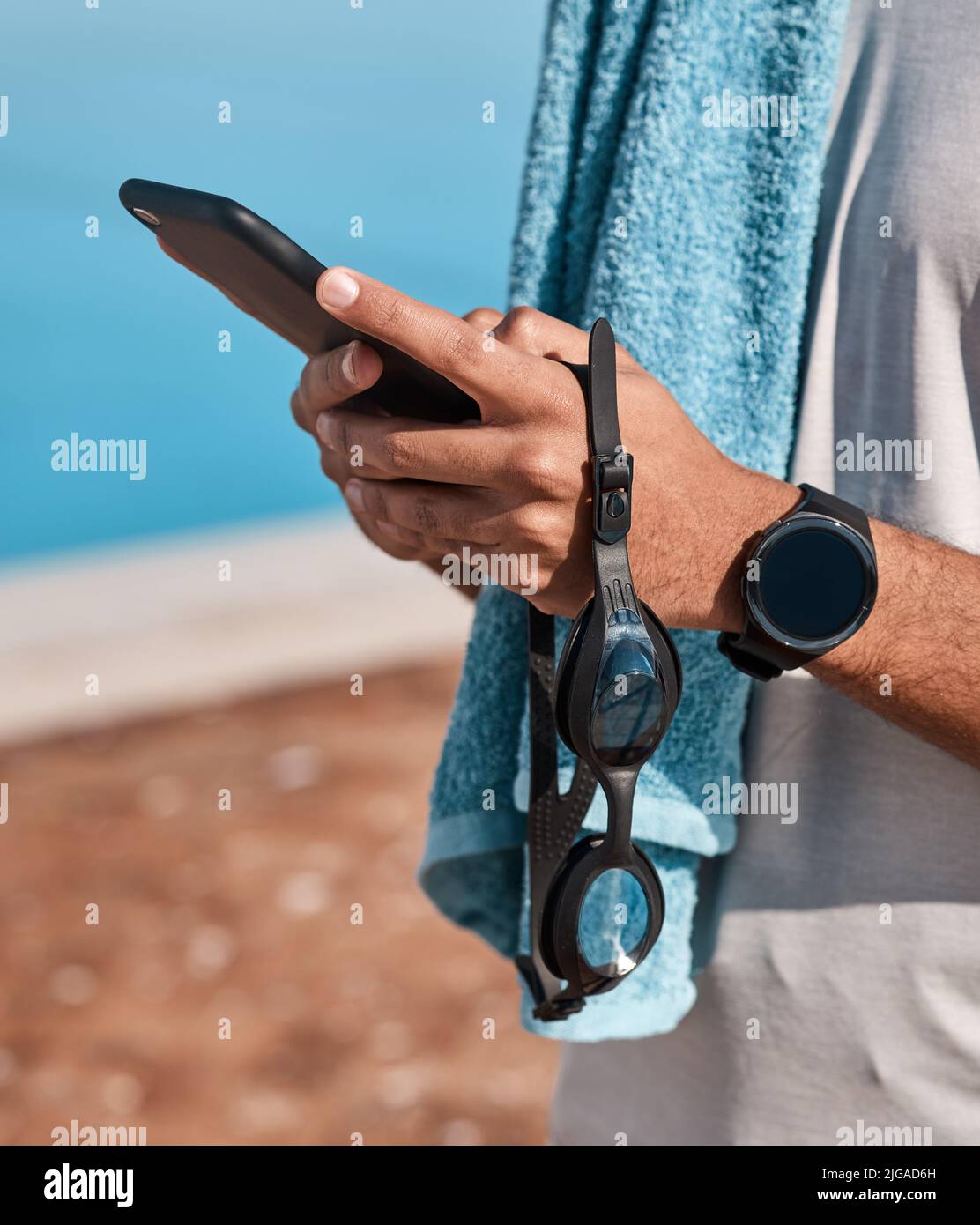 Torna presto, sta per andare in profondità. Un uomo irriconoscibile che usa uno smartphone prima di andare a nuotare. Foto Stock