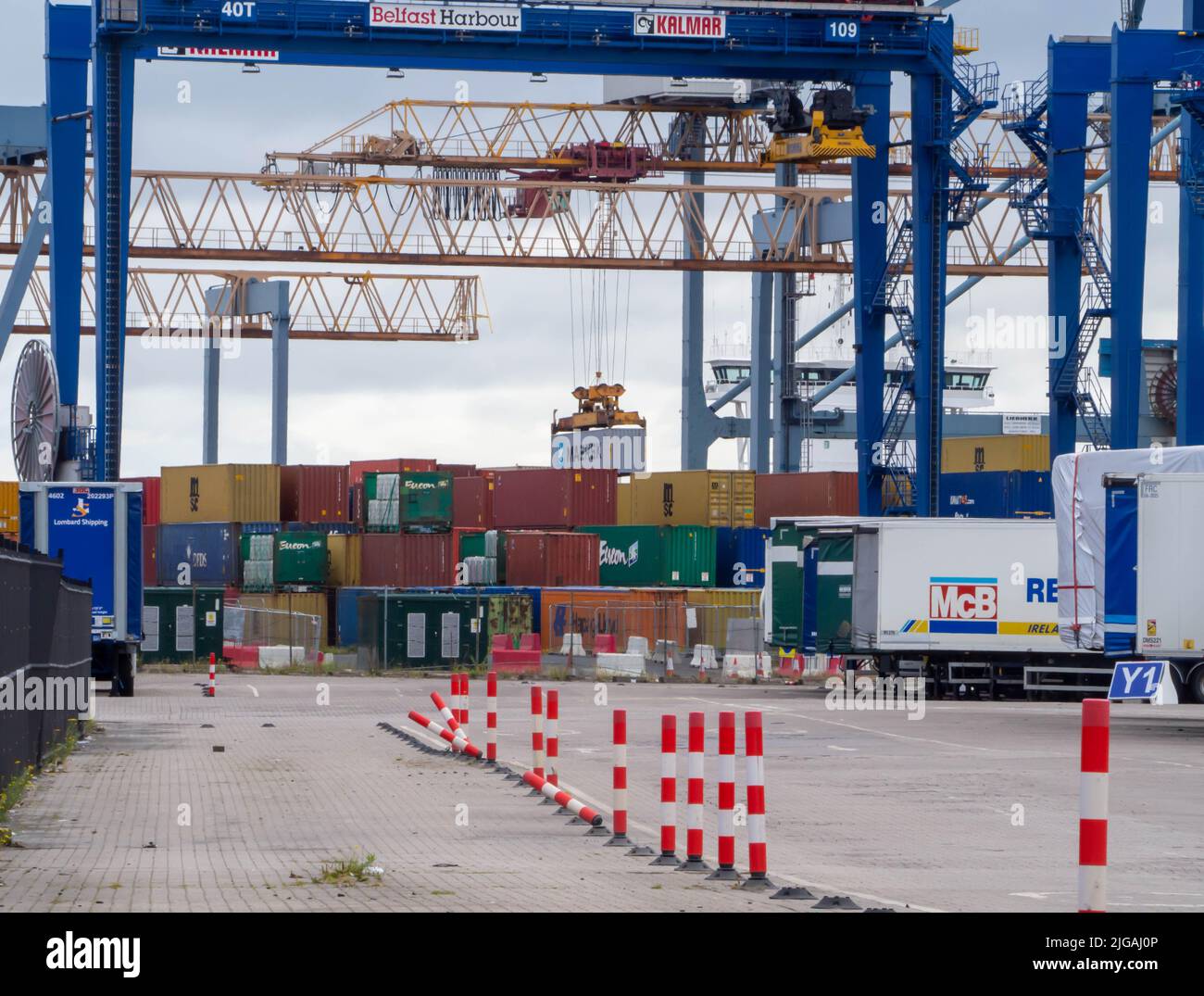 Belfast Docks occupato con lo spostamento di un contenitore a mezz'aria per essere caricato su una nave container in attesa pronta per l'esportazione Foto Stock