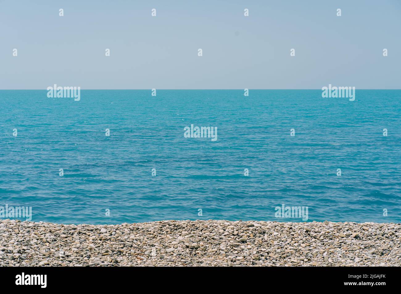 Banca di ciottoli con il mare e la spiaggia sullo sfondo. Foto Stock