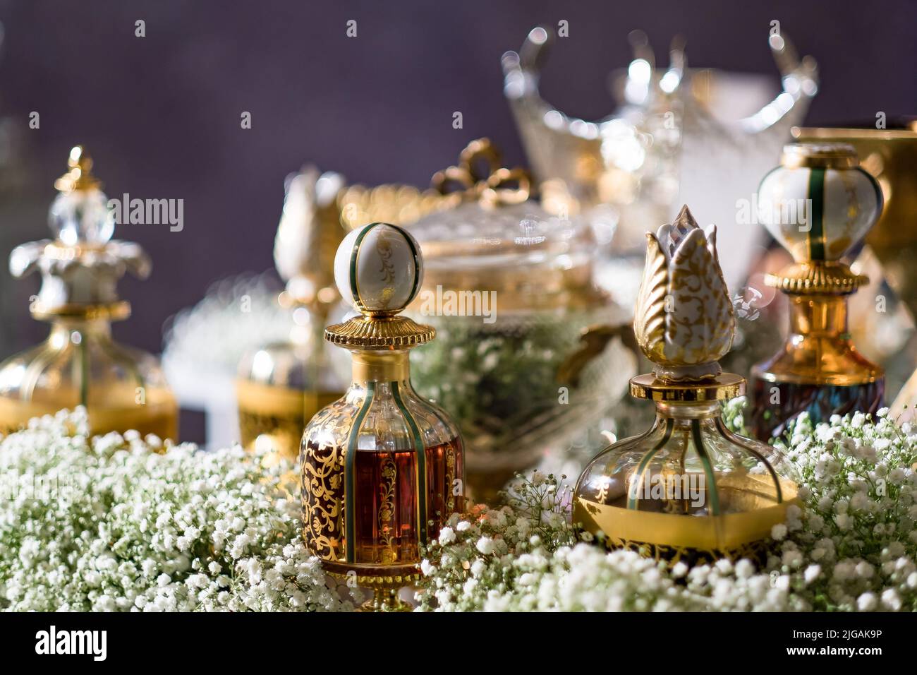 Una varietà di profumi in vetro decorativo e bottiglie di cristallo su un tavolo con il respiro del bambino. Servizio di preparazione all'ingresso per gli ospiti di un matrimonio arabo. Foto Stock