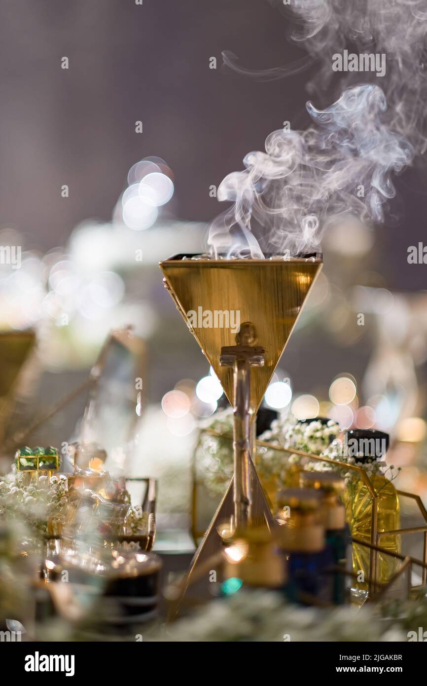 Oud (trucioli di legno di Agar con profumo di muschio) che brucia in un Mabkhara d'oro (censer) su un tavolo con bottiglie di profumo e il respiro del bambino ad un matrimonio arabo. Foto Stock
