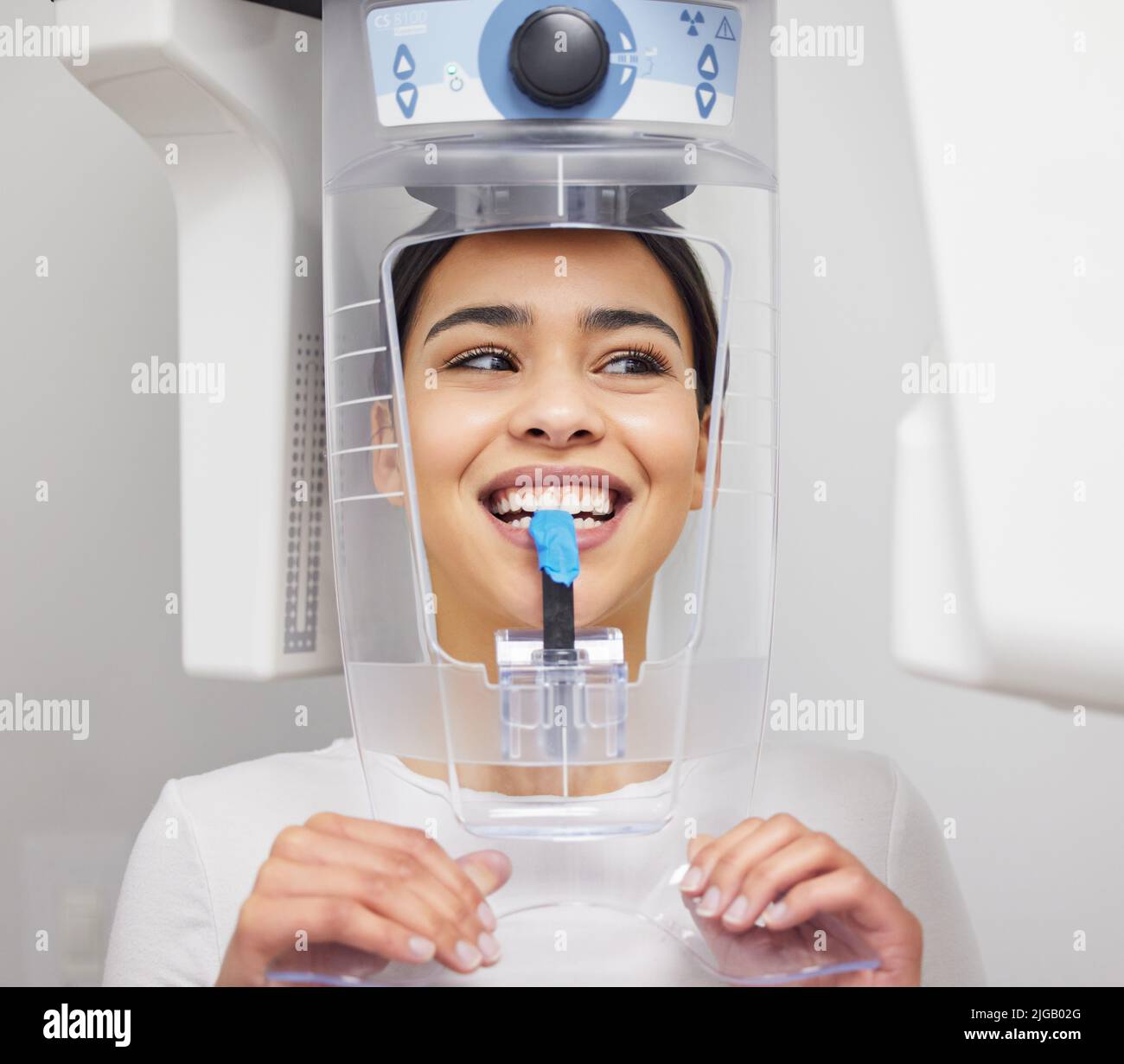 Come perfetto i miei denti guardare. Una giovane donna che usa una macchina a raggi X in un ufficio dentistico. Foto Stock