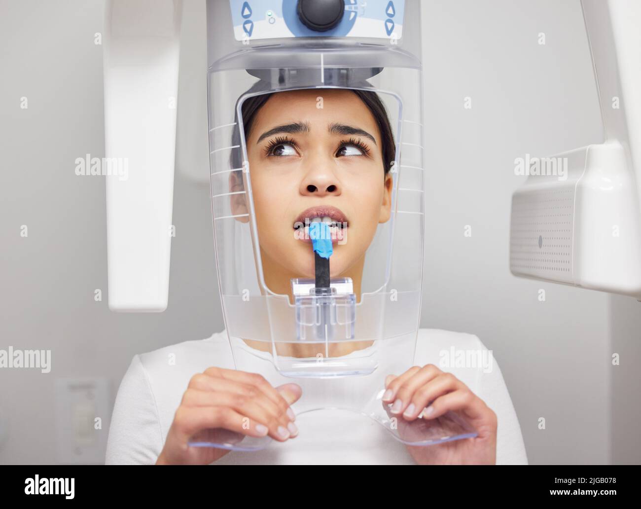 Non mi piace il suono di questa macchina. Una giovane donna che guarda ansiosa mentre usa una macchina a raggi X in un ufficio dentistico. Foto Stock