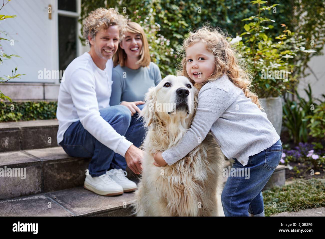 HES come suo fratello maggiore. Ritratto di una bella famiglia che gioca con il loro cane mentre si siede fuori insieme. Foto Stock