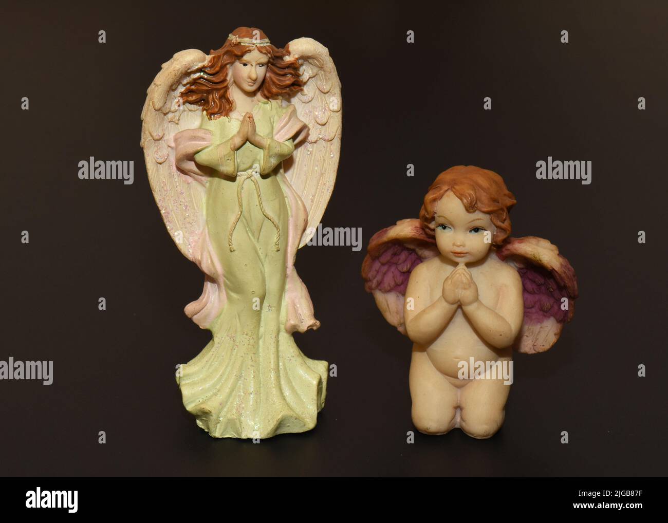 Una donna in ceramica e un angelo bambino isolato su uno sfondo nero Foto Stock