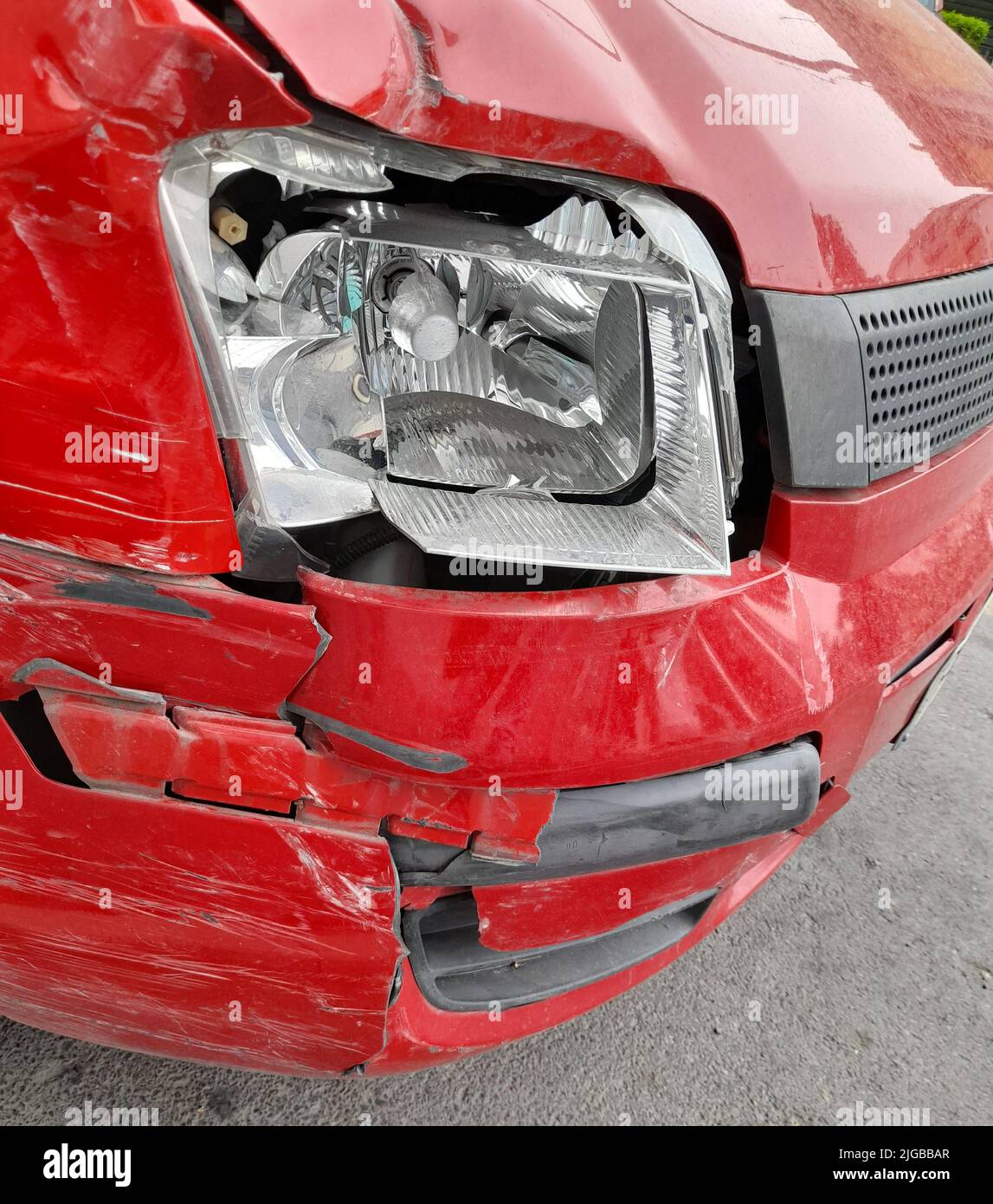 Un faro rotto di un'auto rossa in un negozio Foto Stock