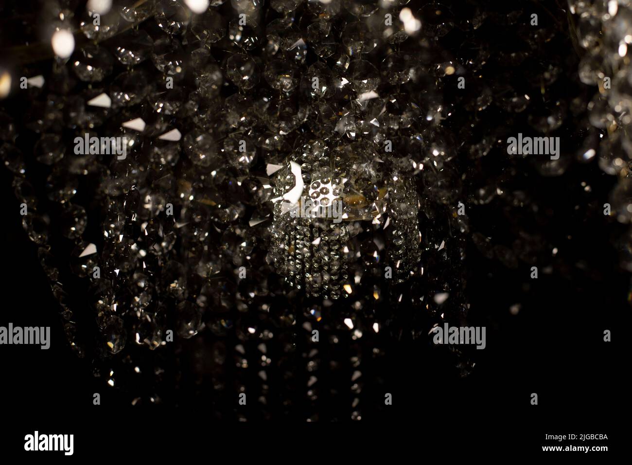 Tessuto di vetro trasparente in luce artificiale. Dettagli di lampadario in vetro scuro. Sfondo caotico di vetro in luce soffusa. Foto Stock