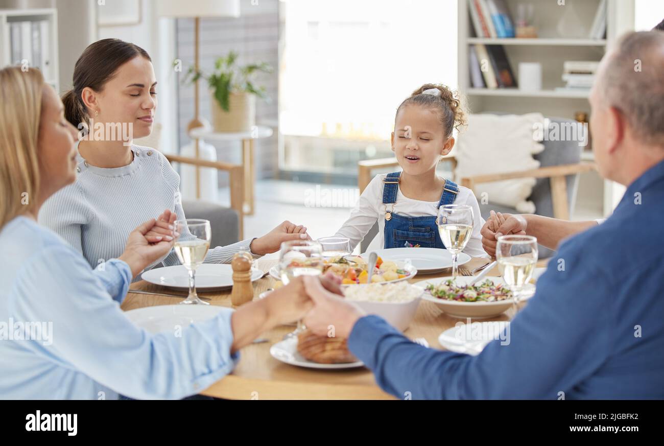 Una tradizione antica come il tempo, una bella famiglia che benedice il cibo con una preghiera a tavola insieme a casa. Foto Stock