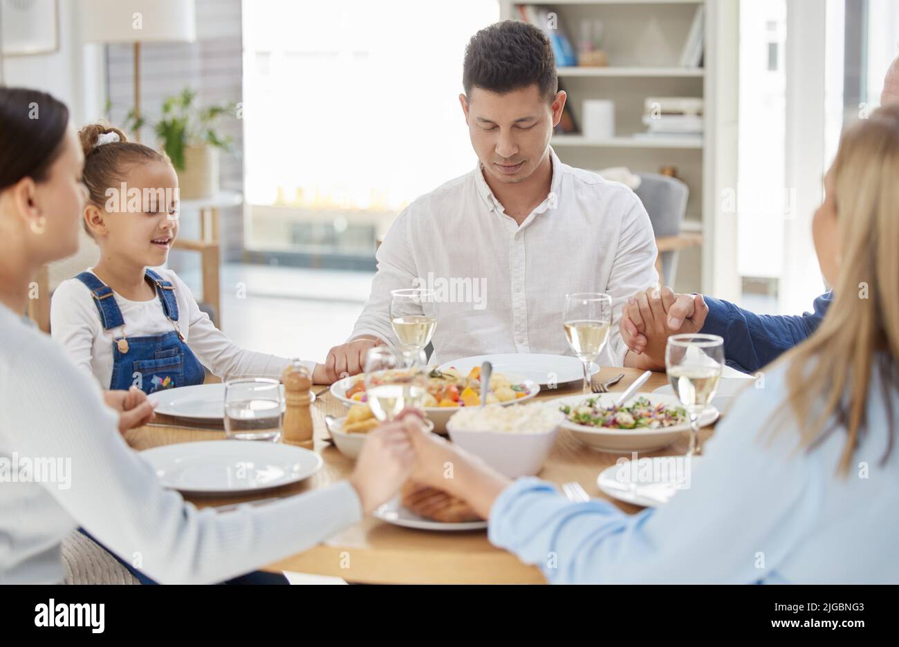 Benedici questo pasto ai nostri corpi, o Dio, una bella famiglia che benedica il cibo con una preghiera a tavola insieme a casa. Foto Stock