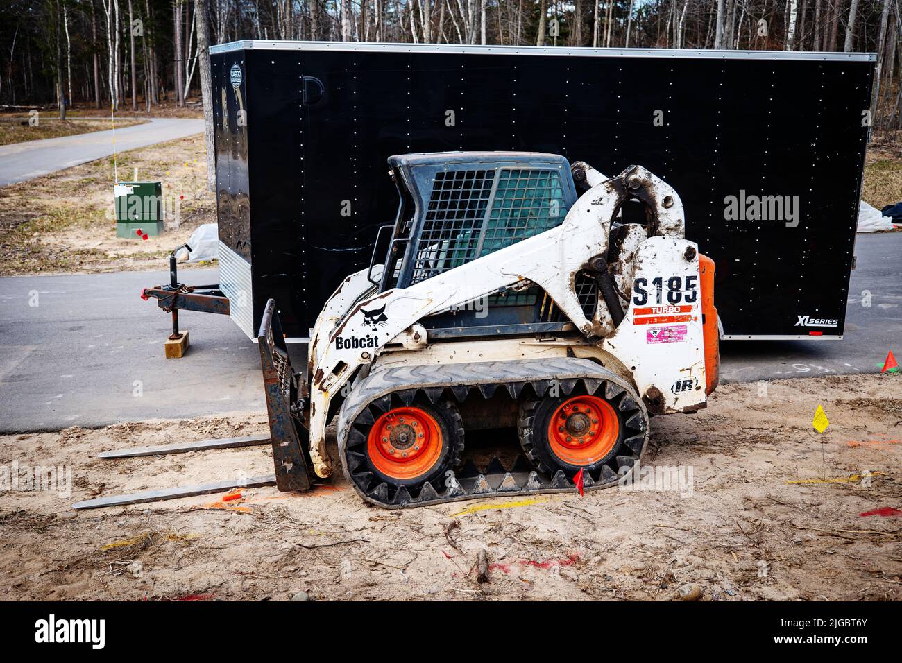 CROW WING CO, MN - 5 MAGGIO 2022: Bobcat con carrello elevatore su terra e un rimorchio coperto nero sul marciapiede stradale. Foto Stock