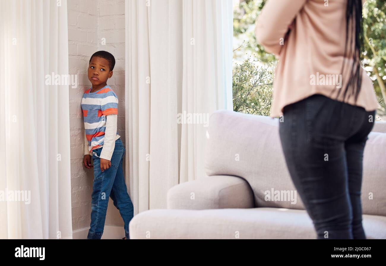 Devo davvero stare qui: Un ragazzino che si trova in un angolo come punizione a casa. Foto Stock