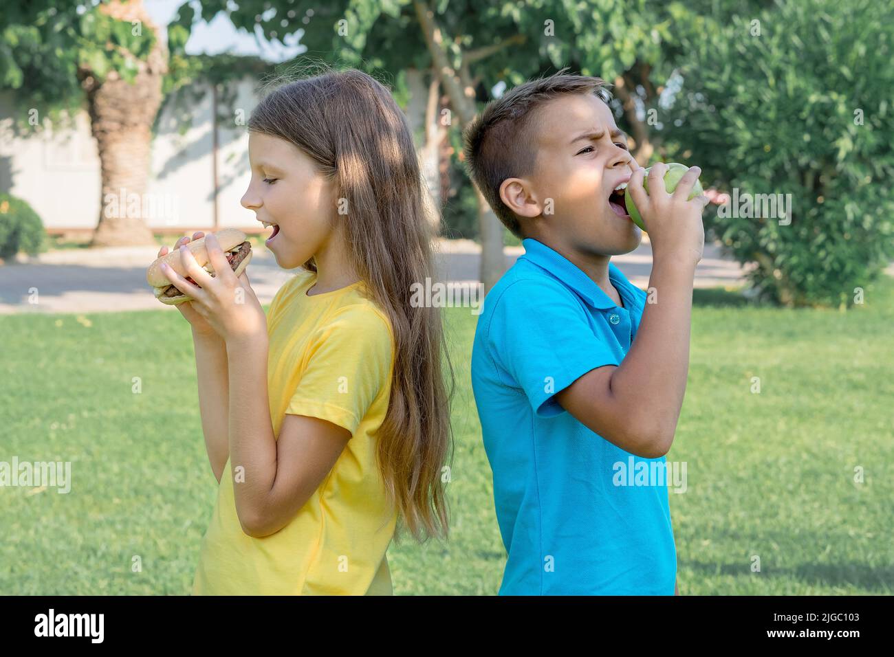 Gli scolari mangiano hamburger nel parco. Pranzo dopo scuola. Foto Stock