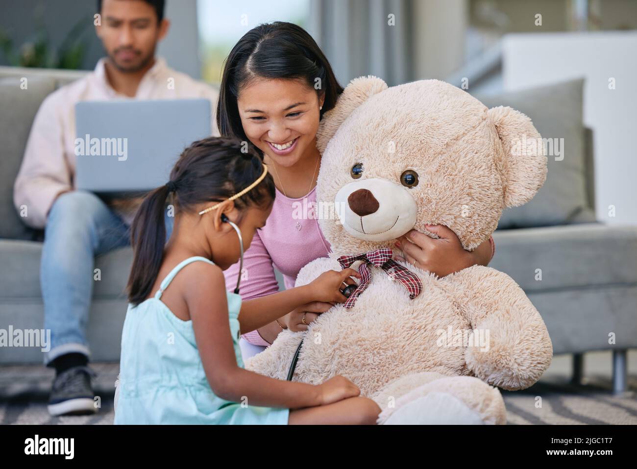 Forse stai alzando un futuro dottore. Una bambina che gioca dottore con sua madre usando il suo orsacchiotto. Foto Stock