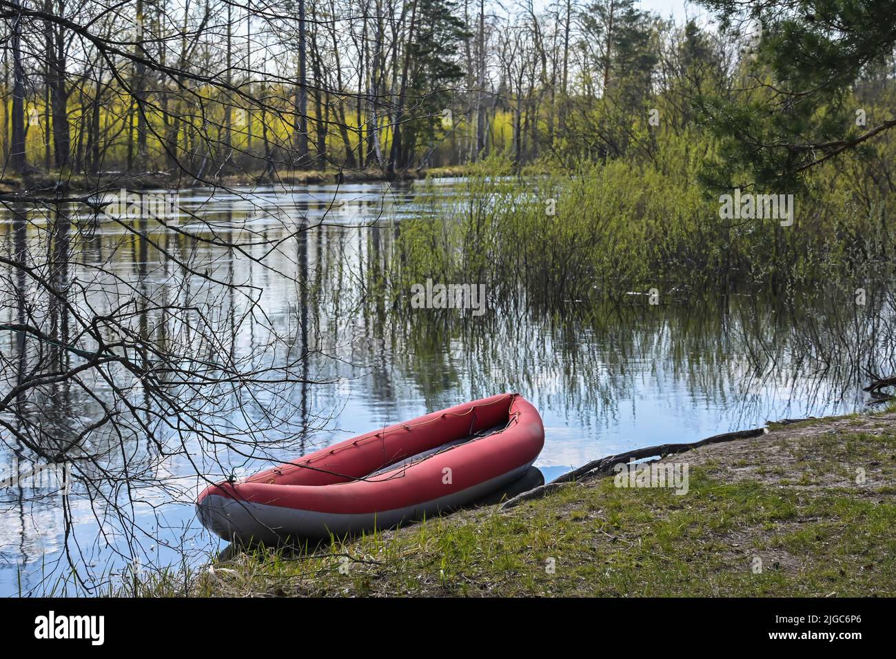Kayak gonfiabile rosso vicino alla riva del fiume foresta. Passeggiata primaverile al Parco Nazionale. Foto Stock