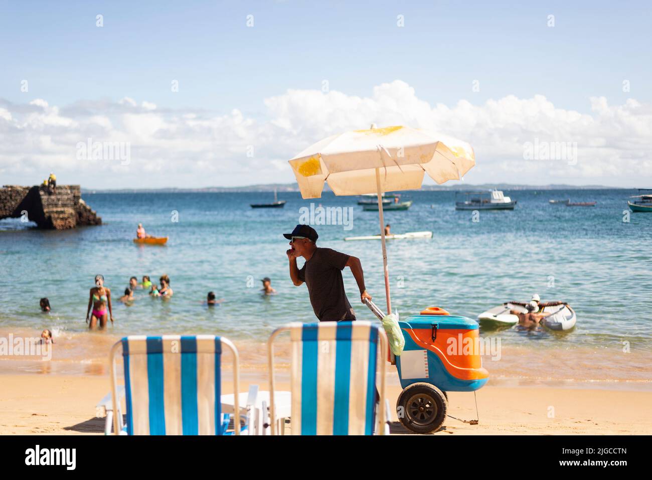 I venditori ambulanti camminano sulla sabbia della spiaggia di Porto da barra a Salvador, Bahia. Foto Stock