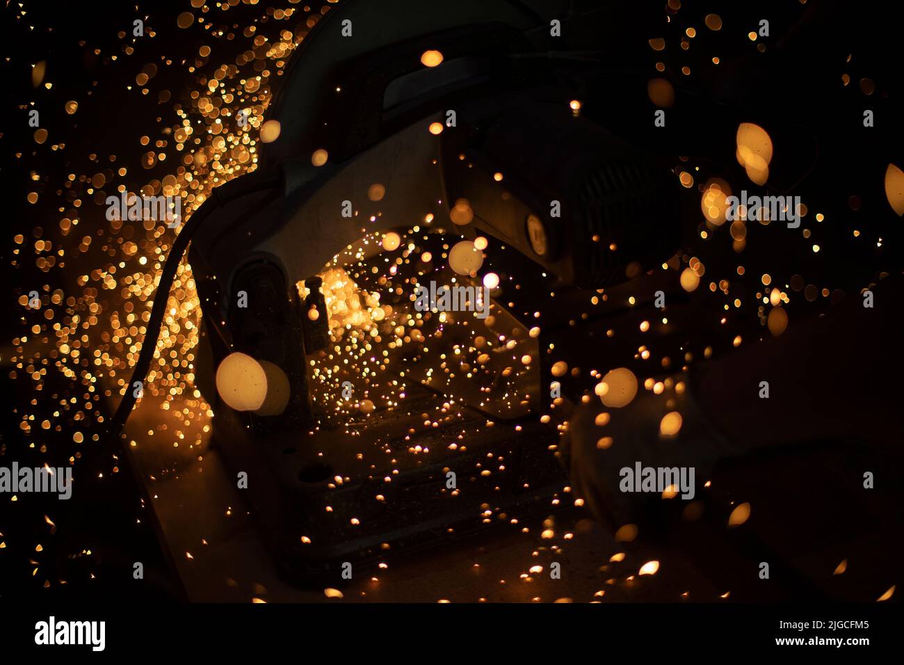 Molte scintille di metallo. La sezionatura è diventata ravvicinata. Dettagli della produzione industriale. Luci brillanti. Foto Stock