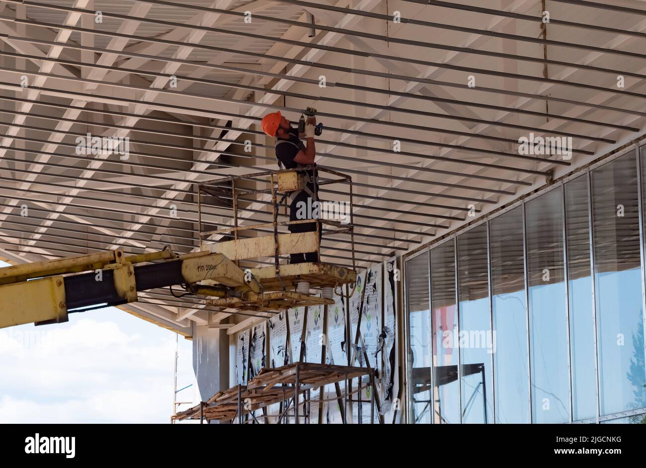 Kazan, Russia. Maggio 20, 2022. Montaggio della struttura a soffitto. Costruzione di un nuovo centro commerciale. Il costruttore è in piedi sul meccanismo di sollevamento. Foto Stock