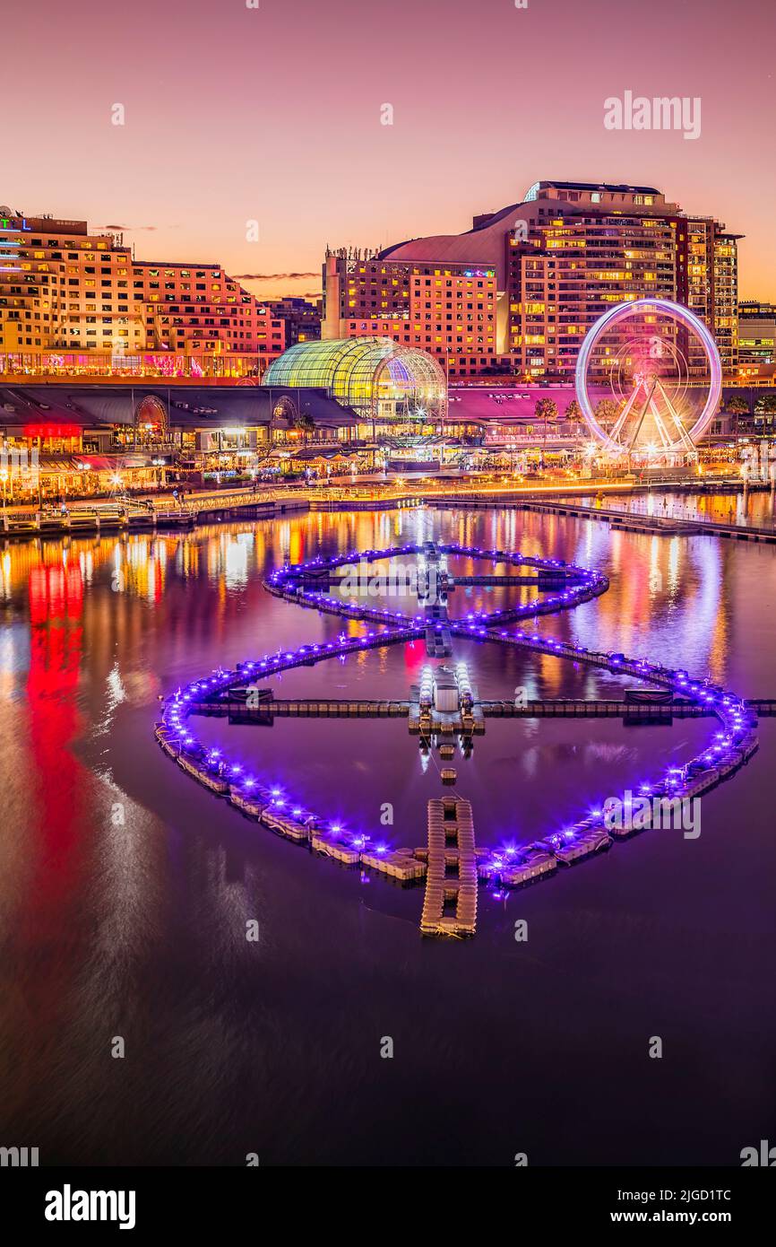 Raffinati ristoranti e caffe' sul lungomare dell'area urbana di Sydney Darling Harbour al Vivid Sydney Light Show e al tramonto rosa. Foto Stock