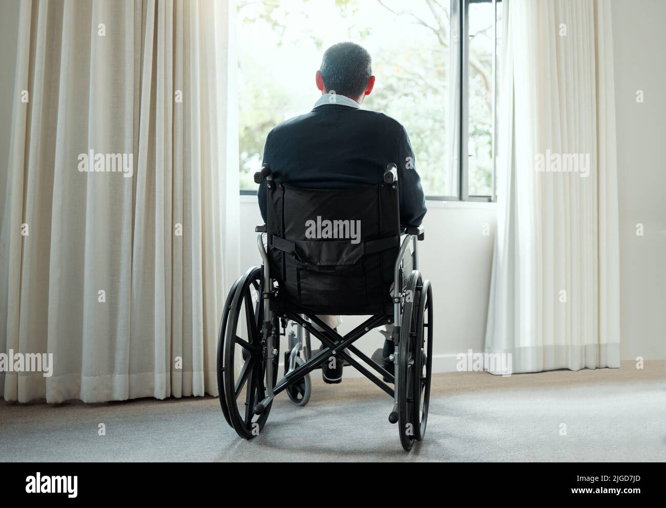 Dimenticato da un mondo che una volta governavamo. Scatto retroguarato di un uomo anziano che gode della vista dalla sua finestra. Foto Stock