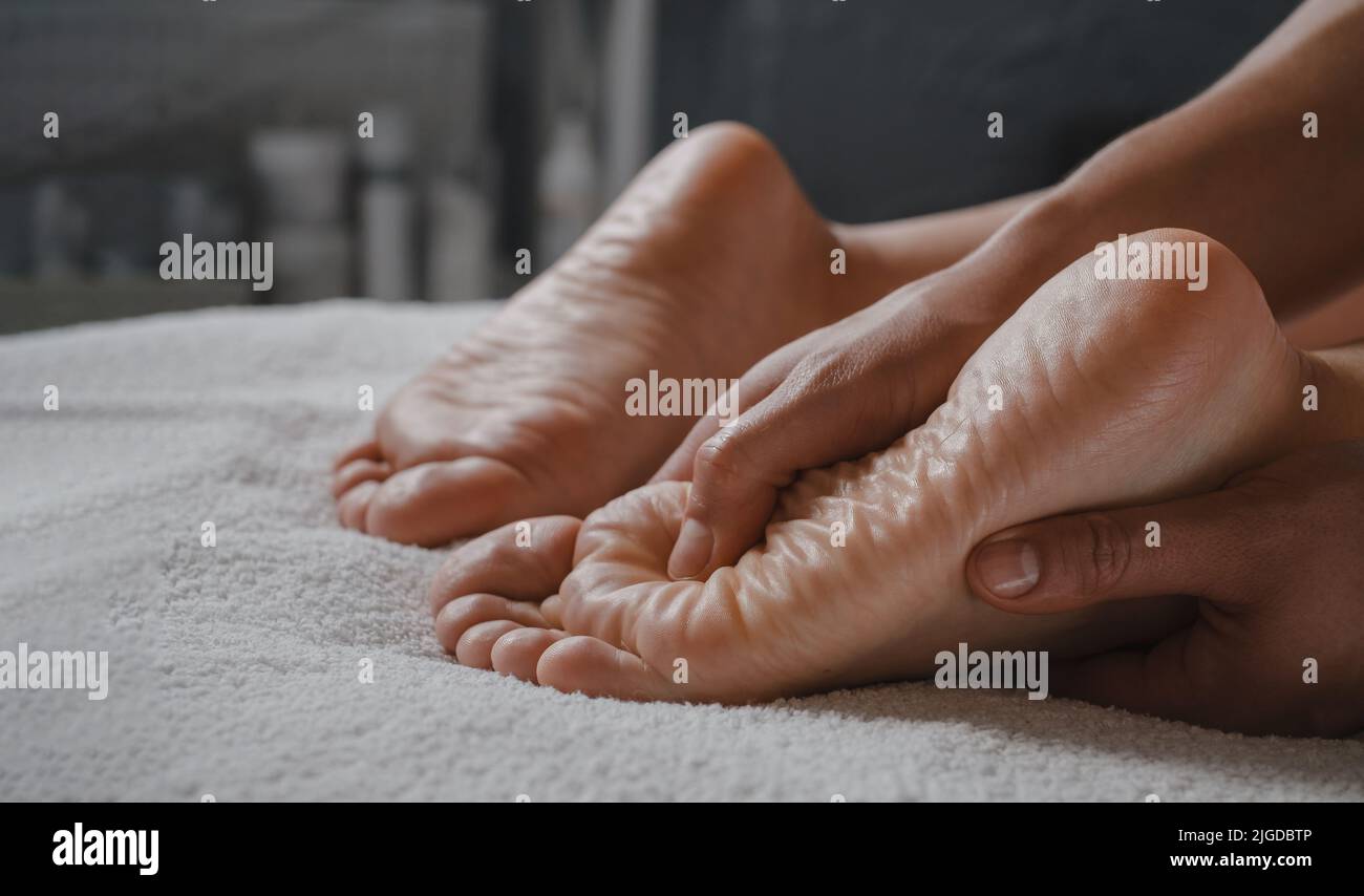 Massaggio benessere donna ai piedi da parte di un massaggiatore professionista presso il centro benessere. Concetto di benessere, di sollievo dallo stress e di ringiovanimento. Cura del corpo Foto Stock