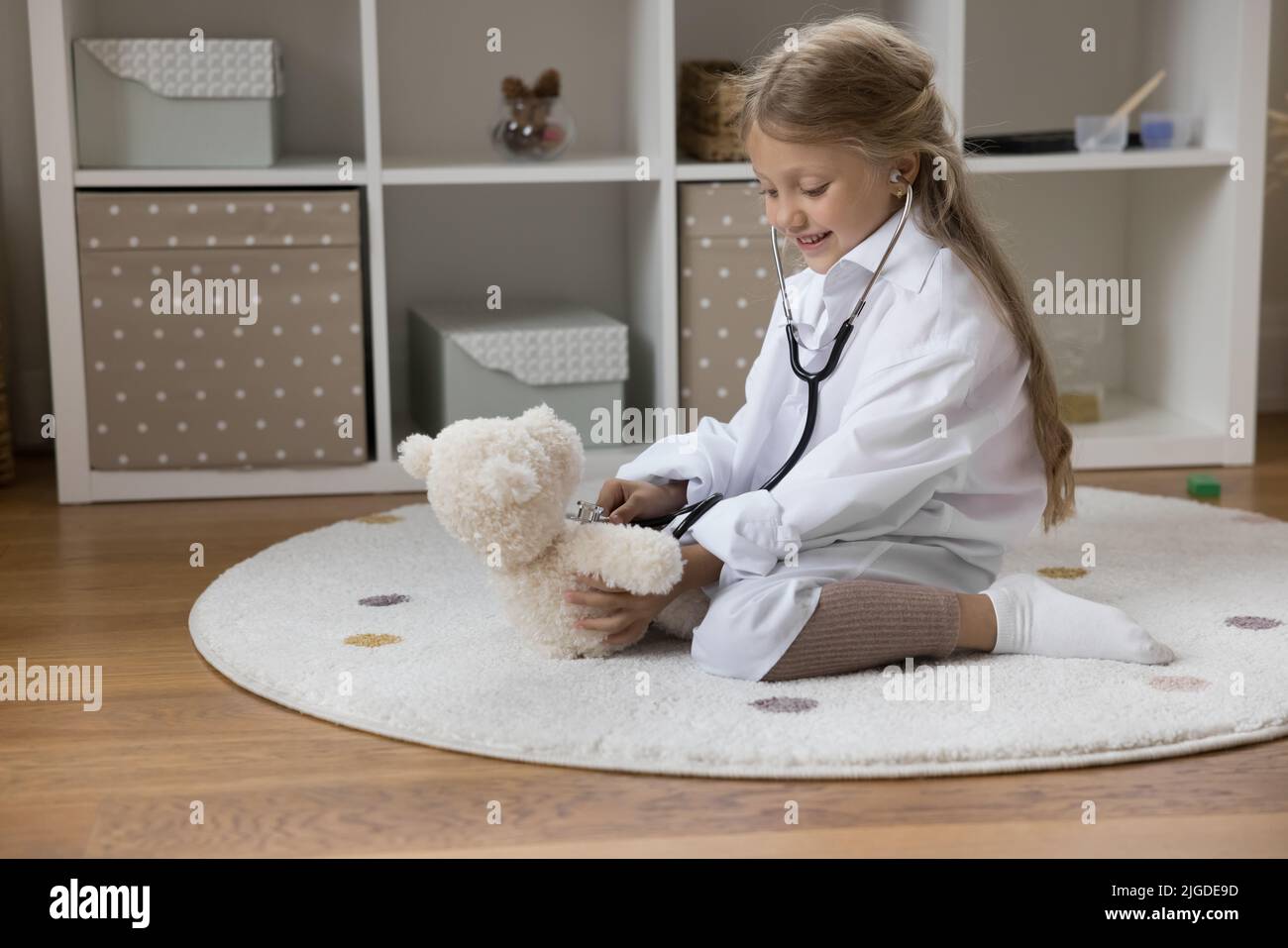 Ragazza felice che indossa un cappotto bianco medico che gioca medico pediatra Foto Stock