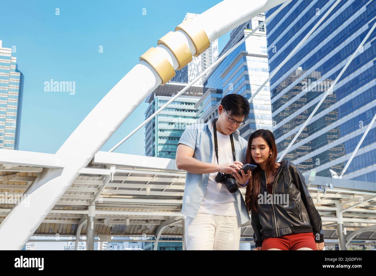 asia city travel. sorridente giovane coppia asiatica che guarda lo smartphone per cercare informazioni di viaggio e la mappa della posizione da viaggio applicazione. Foto Stock
