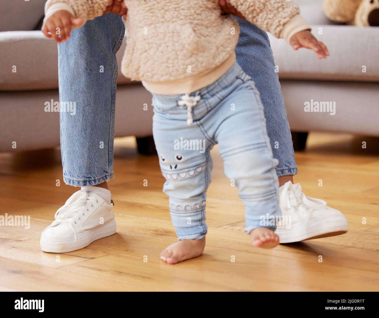 Malati essere lì per i vostri primi passi e ogni altra pietra miliare dopo che. Un bambino imparare a camminare con l'aiuto di sua madre. Foto Stock