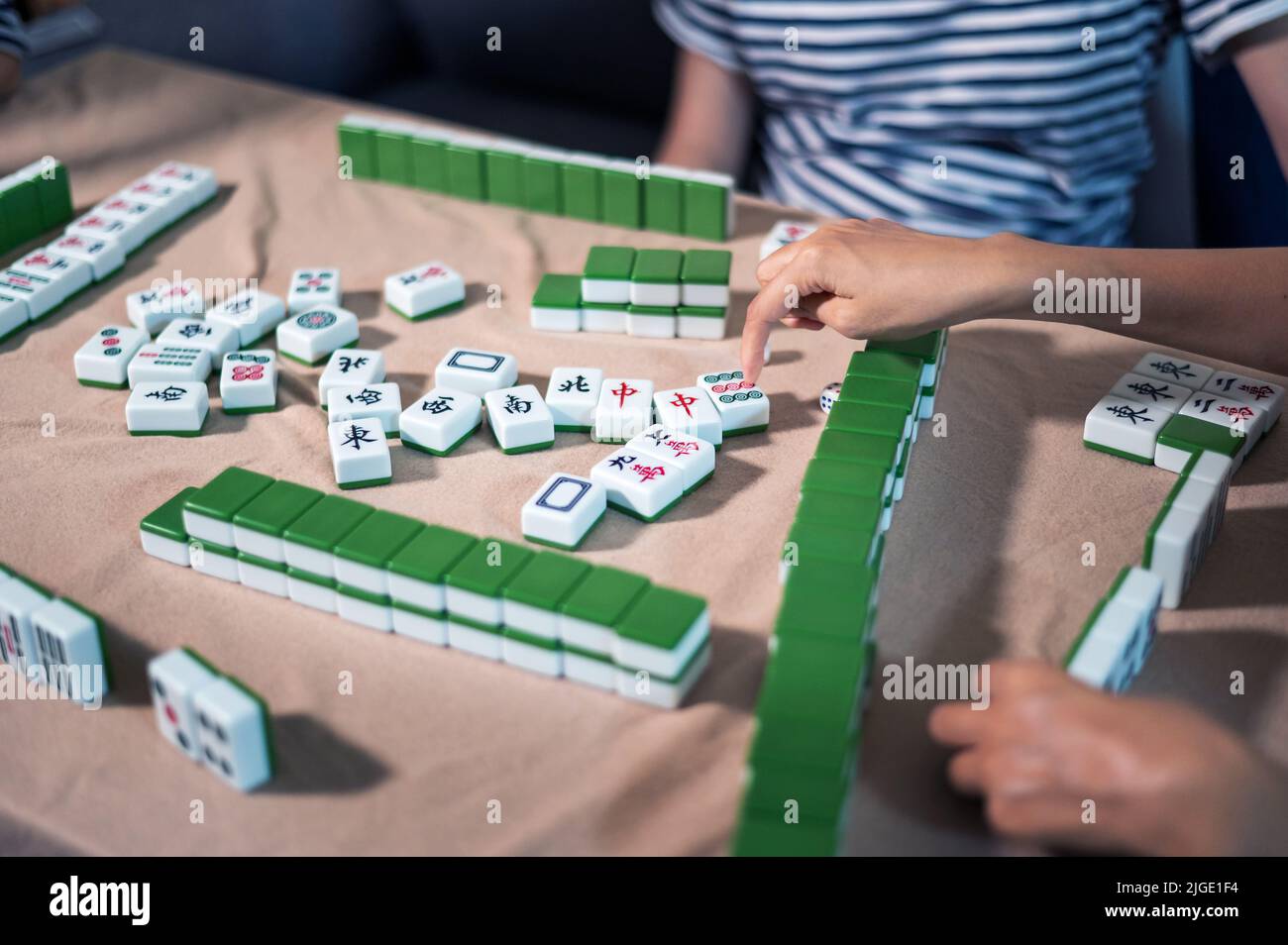 Amici femminili che giocano a mahjong tradizionale gioco da tavolo cinese a casa. Traduzione: Il testo Tile mostra caratteri cinesi per i numeri da 1 a 9 e si Foto Stock
