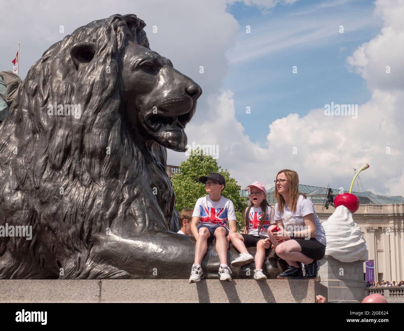 Festeggiatori in Trafalgar Square durante il Giubileo del platino della Regina 2022 seduti su leoni scolpiti Foto Stock