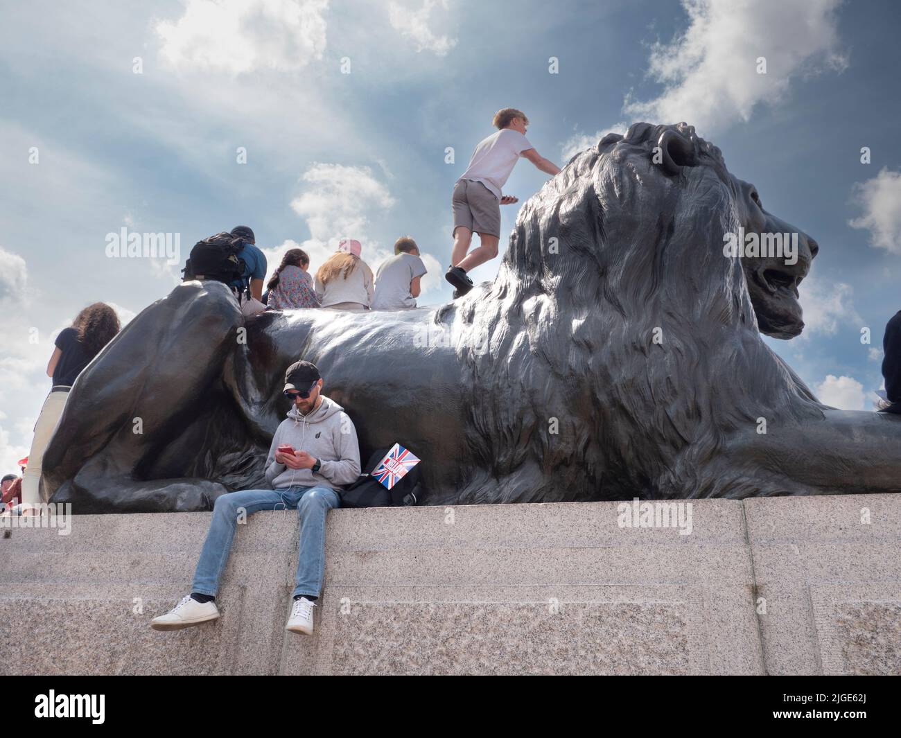 Festeggiatori in Trafalgar Square durante il Giubileo del platino della Regina 2022 seduti su leoni scolpiti Foto Stock