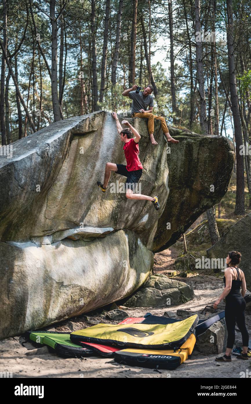 Il giovane atletico sta saltando per la tenuta superiore nel problema famoso e duro del dyno boulder denominato 'rainbow Rocket - 8a'. Fontainebleau, Francia, Europa. Foto Stock
