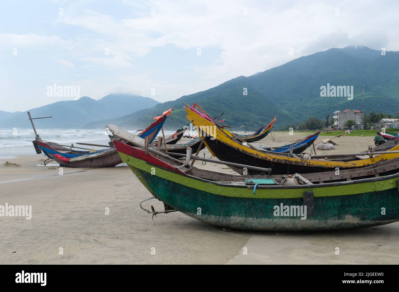 Barche da pesca curve sulla costa del Mar Cinese Meridionale, Lang Co, Vietnam. Spiaggia di sabbia con piccole barche da pesca vietnamite Foto Stock