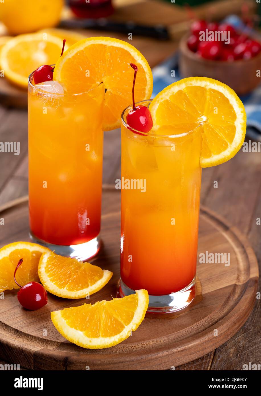 Cocktail tequila all'alba con fetta d'arancia e ciliegia su un rustico tavolo in legno Foto Stock