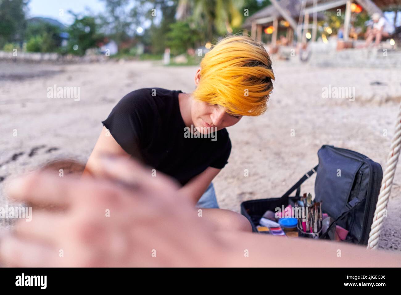 Donna che dipinge una donna durante una sessione di pittura del corpo sulla spiaggia Foto Stock