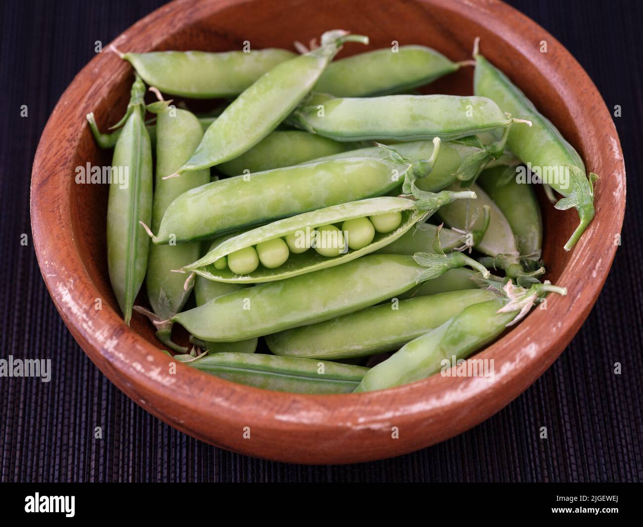Piselli verdi in una ciotola di legno. Primo piano. Foto Stock