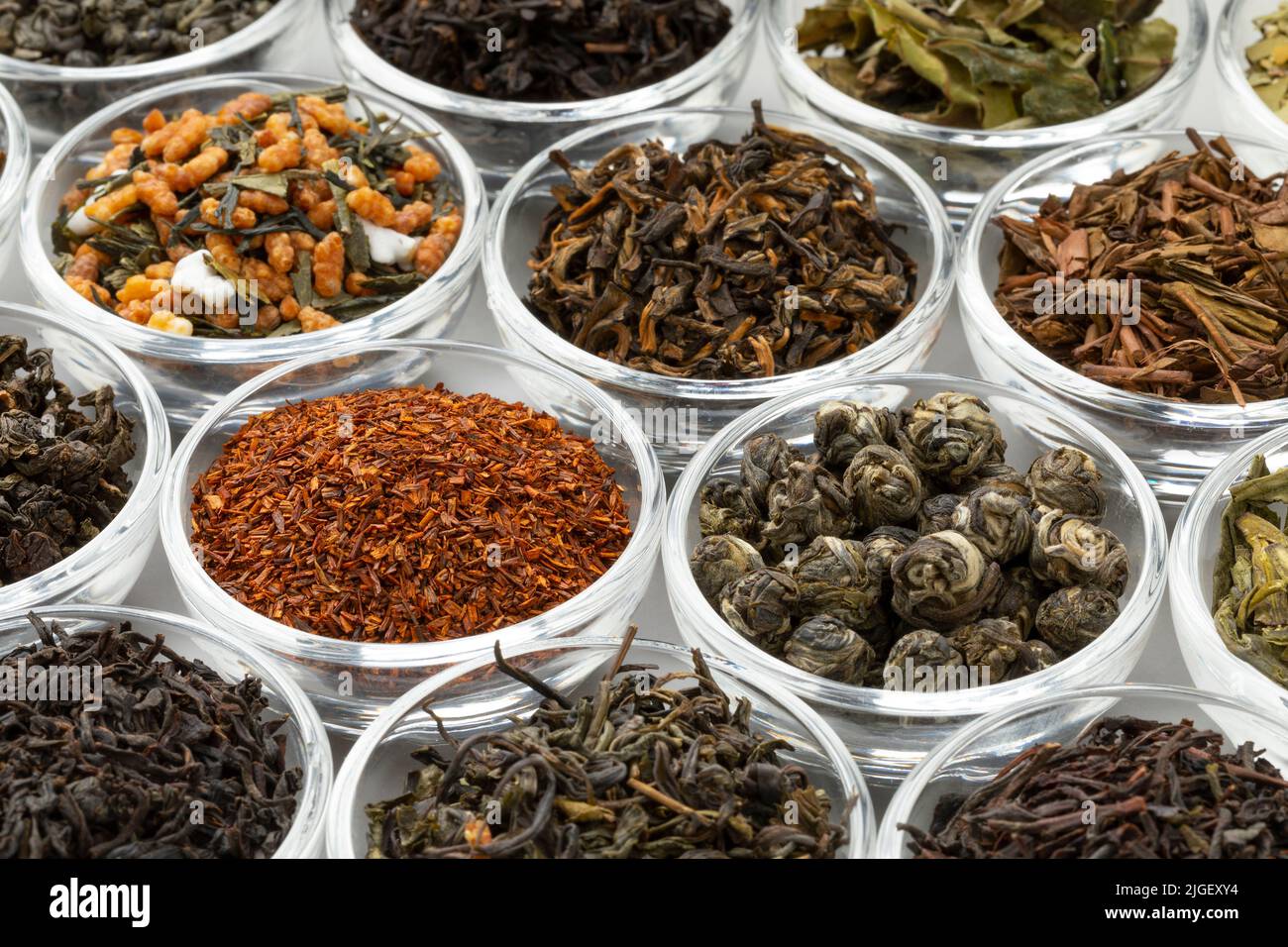 Le ciotole di Glas con una varietà di foglie di tè essiccate diverse da Cina, India, Giappone e Sud Africa close up full frame Foto Stock