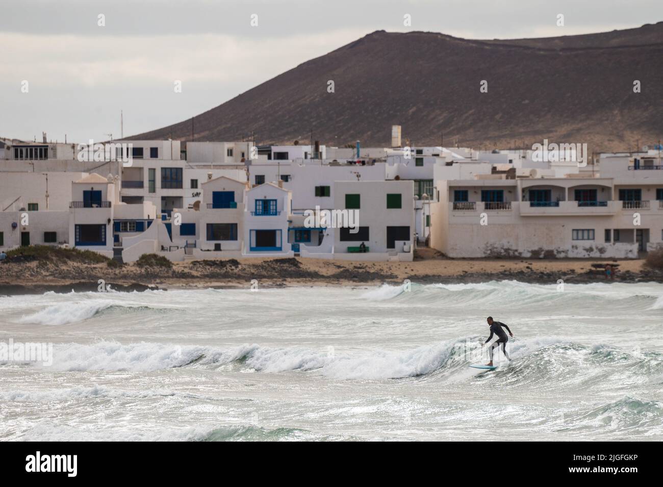 Un uomo che naviga a Famara Beach, sulla costa nord-occidentale dell'isola vulcanica di Lanzarote. Foto Stock