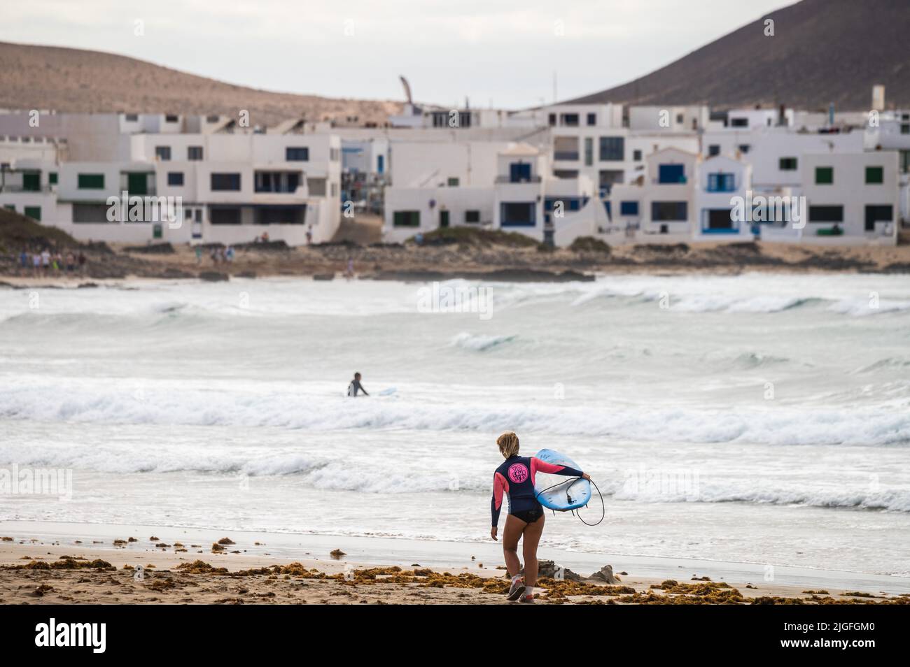 Chi pratica il surf a Famara Beach, sulla costa nord-occidentale dell'isola vulcanica di Lanzarote. Foto Stock