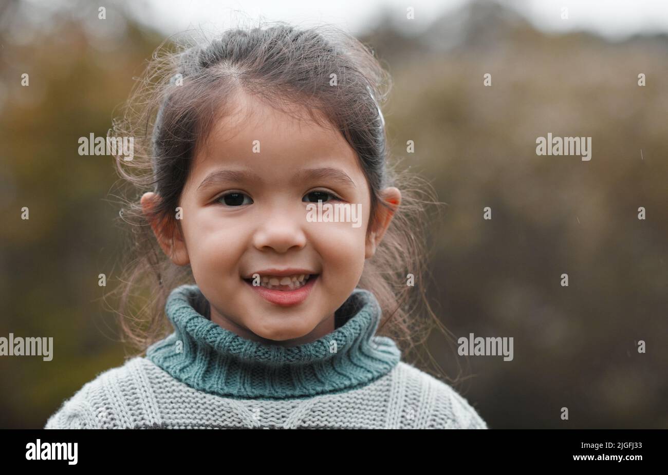 Il parco è il mio posto preferito: Una bambina adorabile in piedi da sola nel parco. Foto Stock