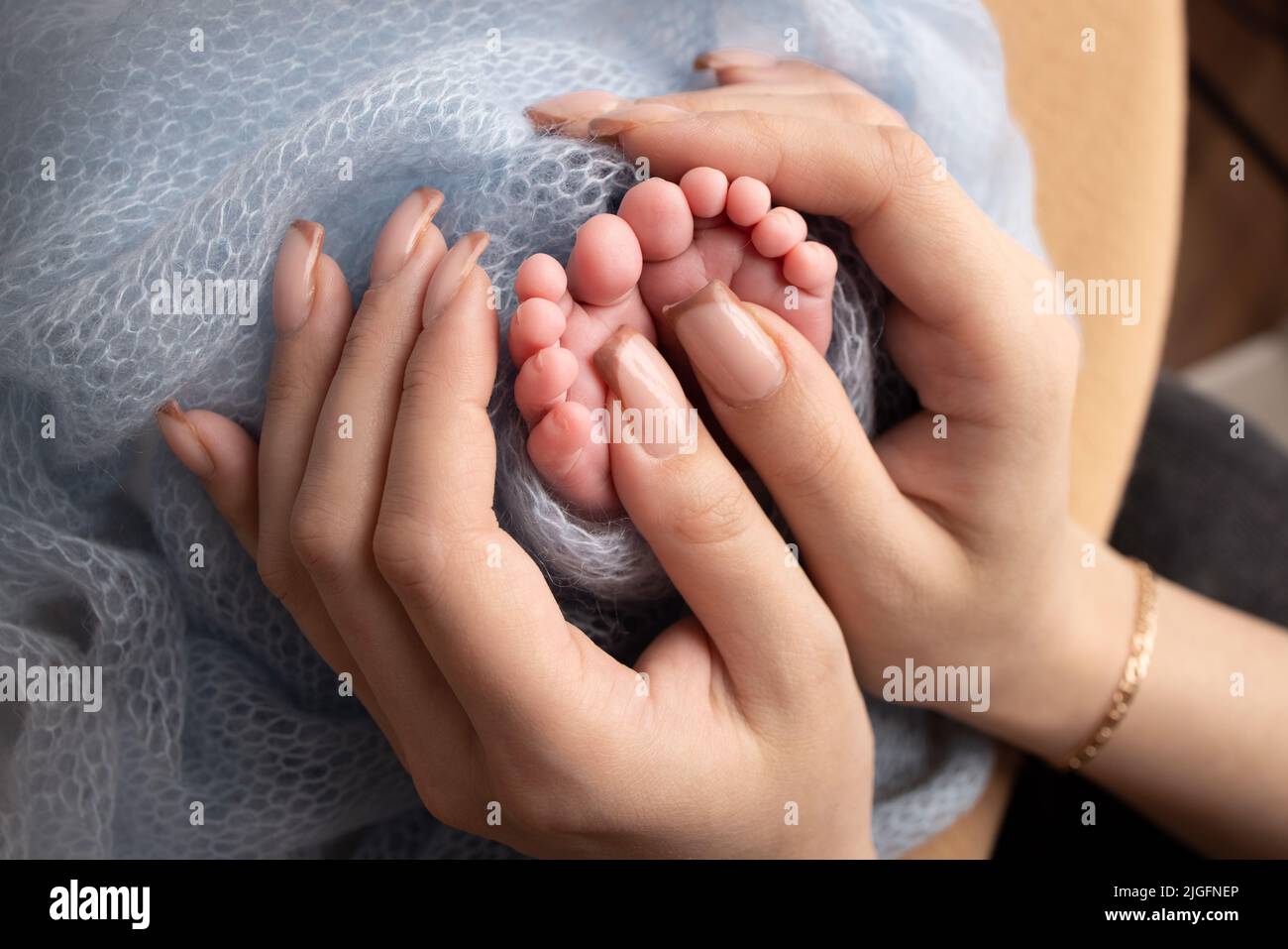 Le palme del padre, la madre stanno tenendo il piede del neonato. Piedi di bambino sulle palme dei genitori. Foto Stock