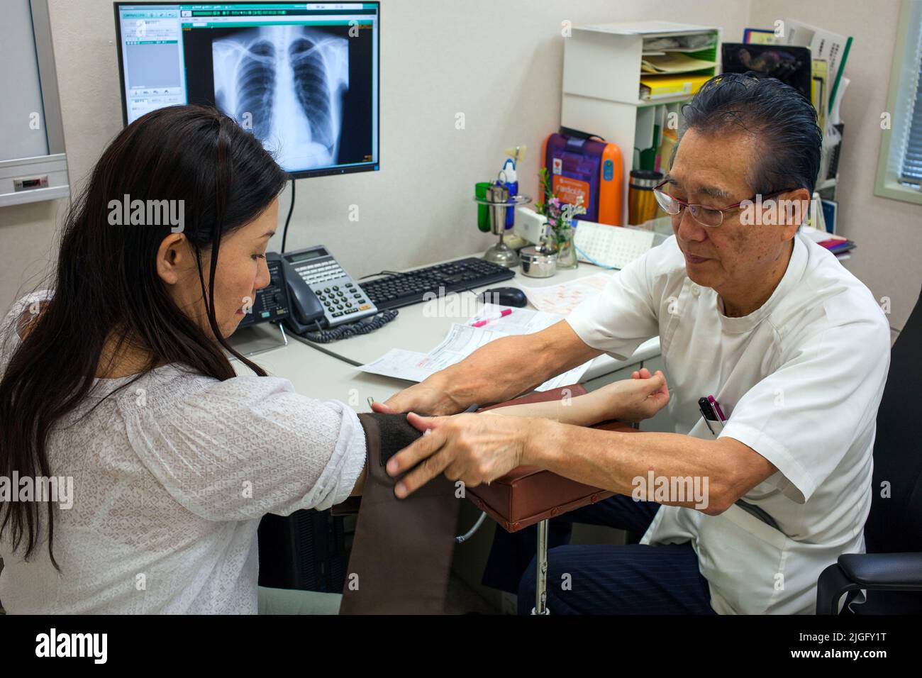Il medico prende la pressione sanguigna dei pazienti alla clinica medica, Ota, Tokyo, Giappone Foto Stock