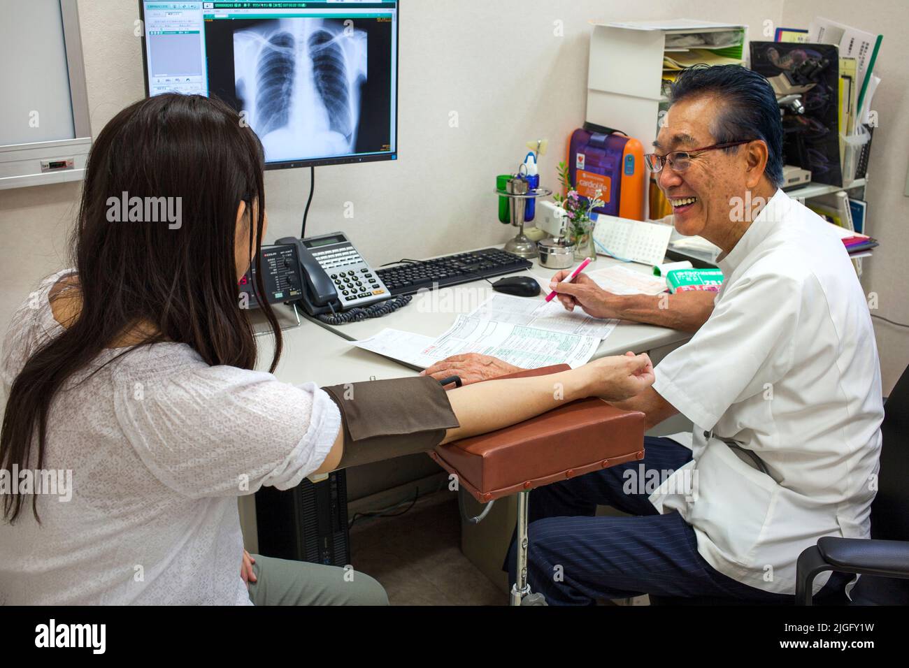 Il medico prende la pressione sanguigna dei pazienti alla clinica medica, Ota, Tokyo, Giappone Foto Stock