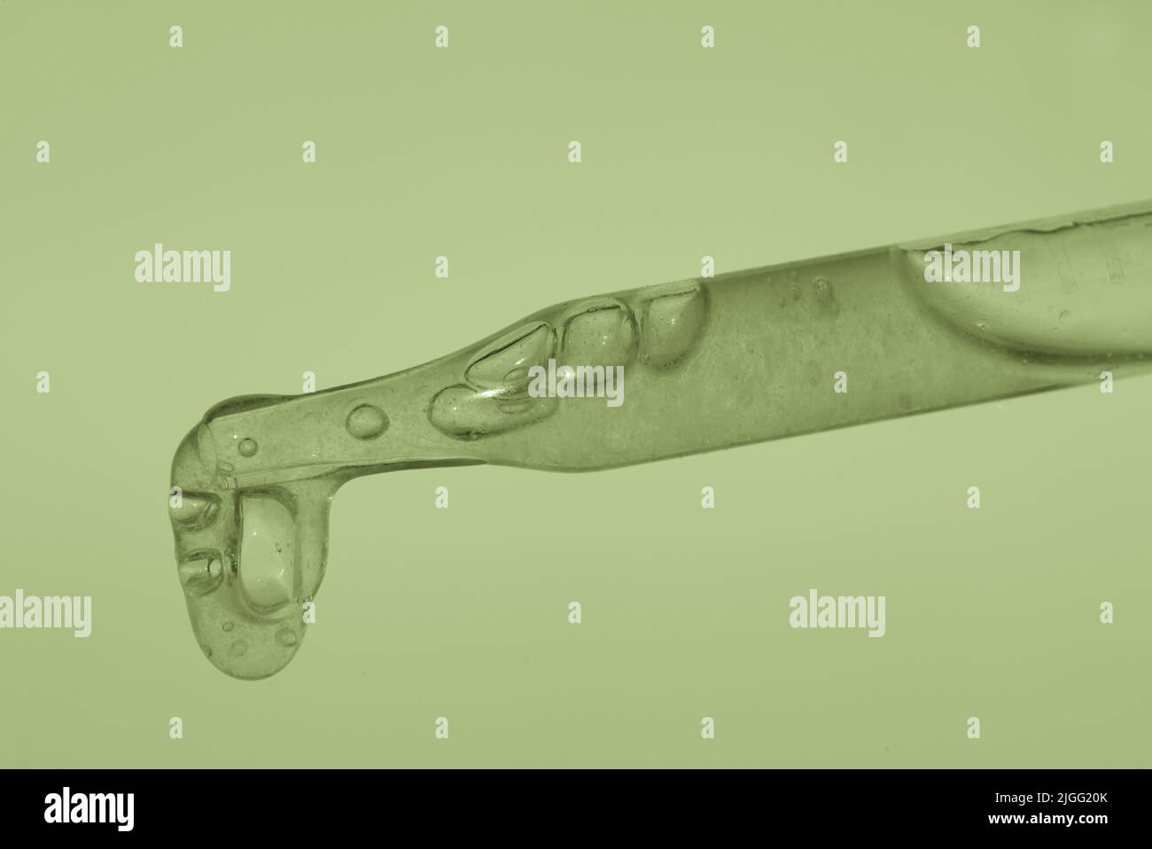 Pipettare con estratto verde su sfondo verde. Consistenza densa, polpa di aloe. Il concetto di estratto vegetale per scopi cosmetici e medicinali. Foto di alta qualità Foto Stock