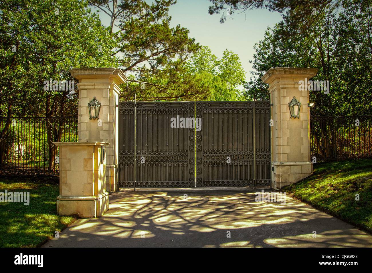 Chiuso imponente cancello di sicurezza di lusso in ferro battuto con tastiera per la proprietà residenziale privata in un quartiere verde con alberi verdi e ombre Foto Stock