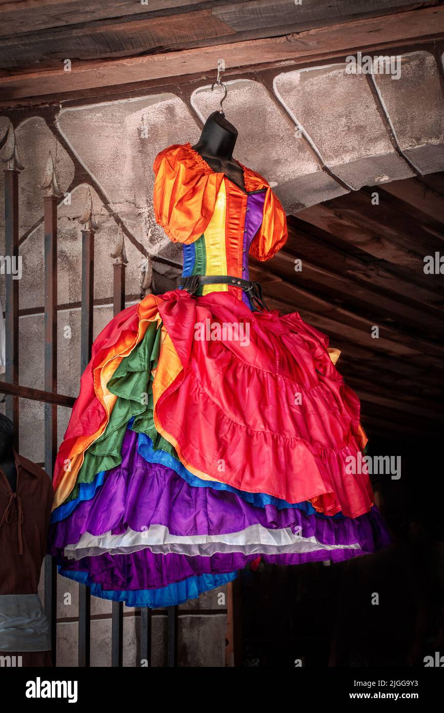 Orgoglio di renassiance fiera colorato vestito con volant appende dalla porta ad arco del negozio del castello Foto Stock