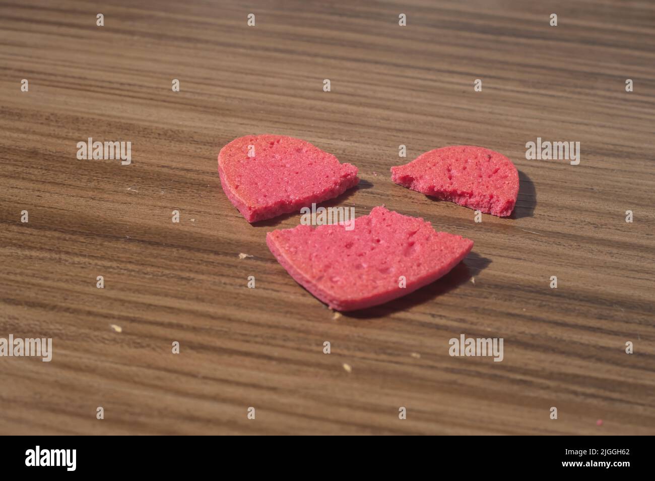 Rottura del lavoro del cuore in pezzi, rottura del biscotto a forma di cuore su un tavolo di legno. Foto Stock