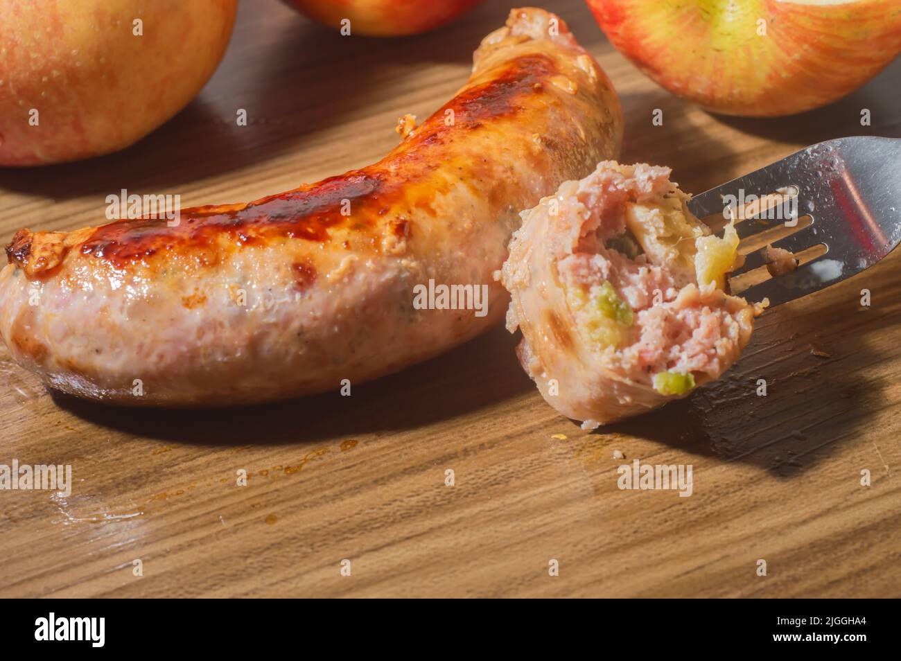 Salsiccia fatta con mela e pepe jaalapeno, su una tavoletta di legno con mele nello spazio per la foto e la copia. Foto Stock